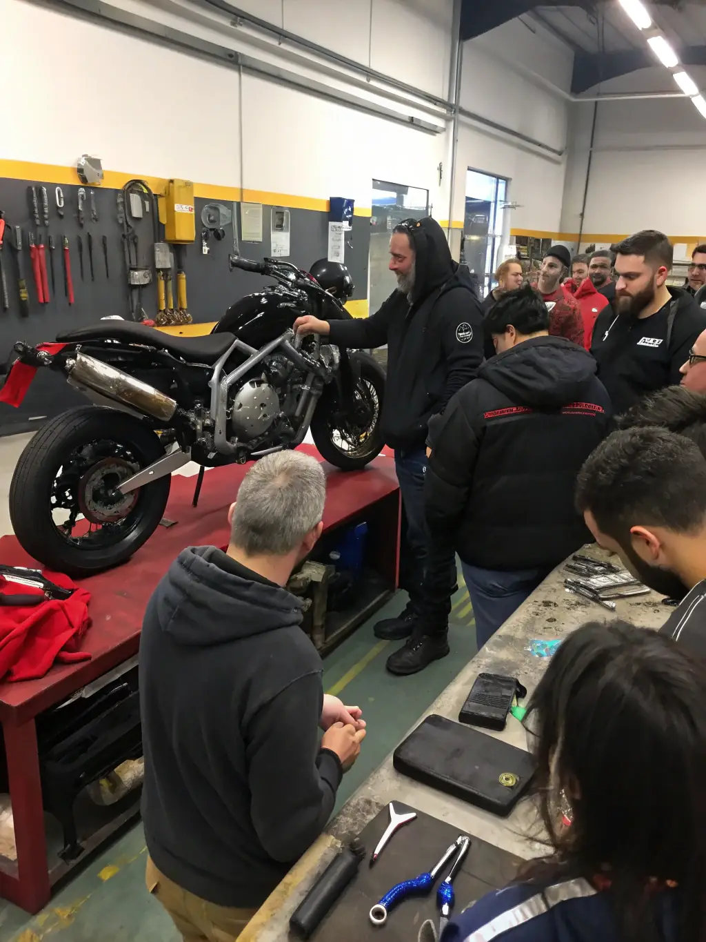 A technical workshop at LEYNHAC-MOTO-QUAD, where experienced instructors are demonstrating maintenance and repair techniques to young participants, fostering technical skills and self-sufficiency.